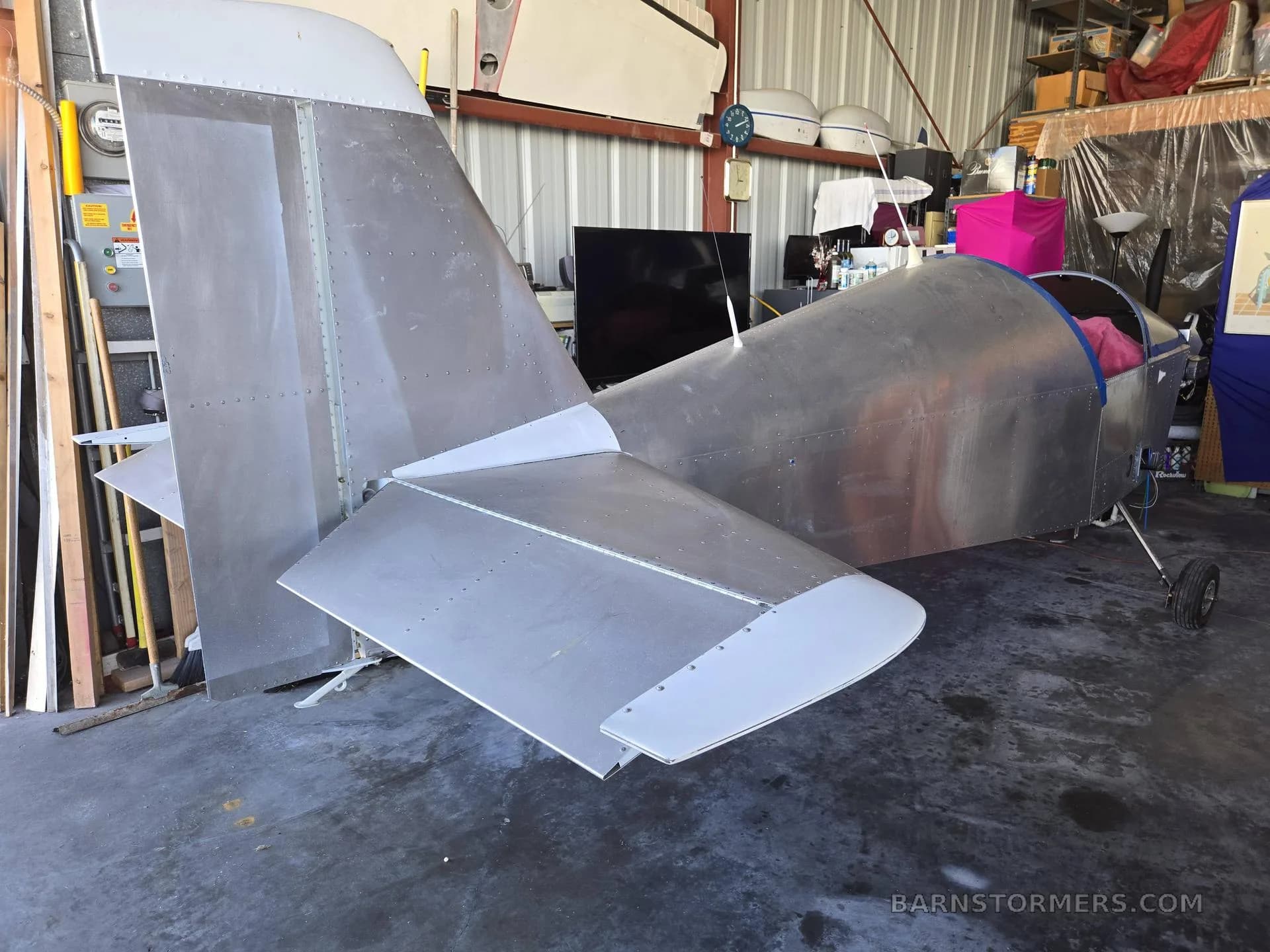 The unpainted rear fuselage and tail section of an aircraft in a hangar.