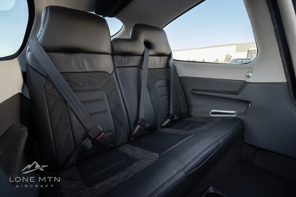 Side view of the black leather rear seats with quilted stitching inside the aircraft cabin.