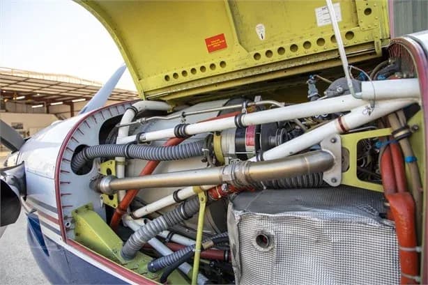 The open engine cowling of a turboprop aircraft reveals complex piping, wiring, and mechanical components.