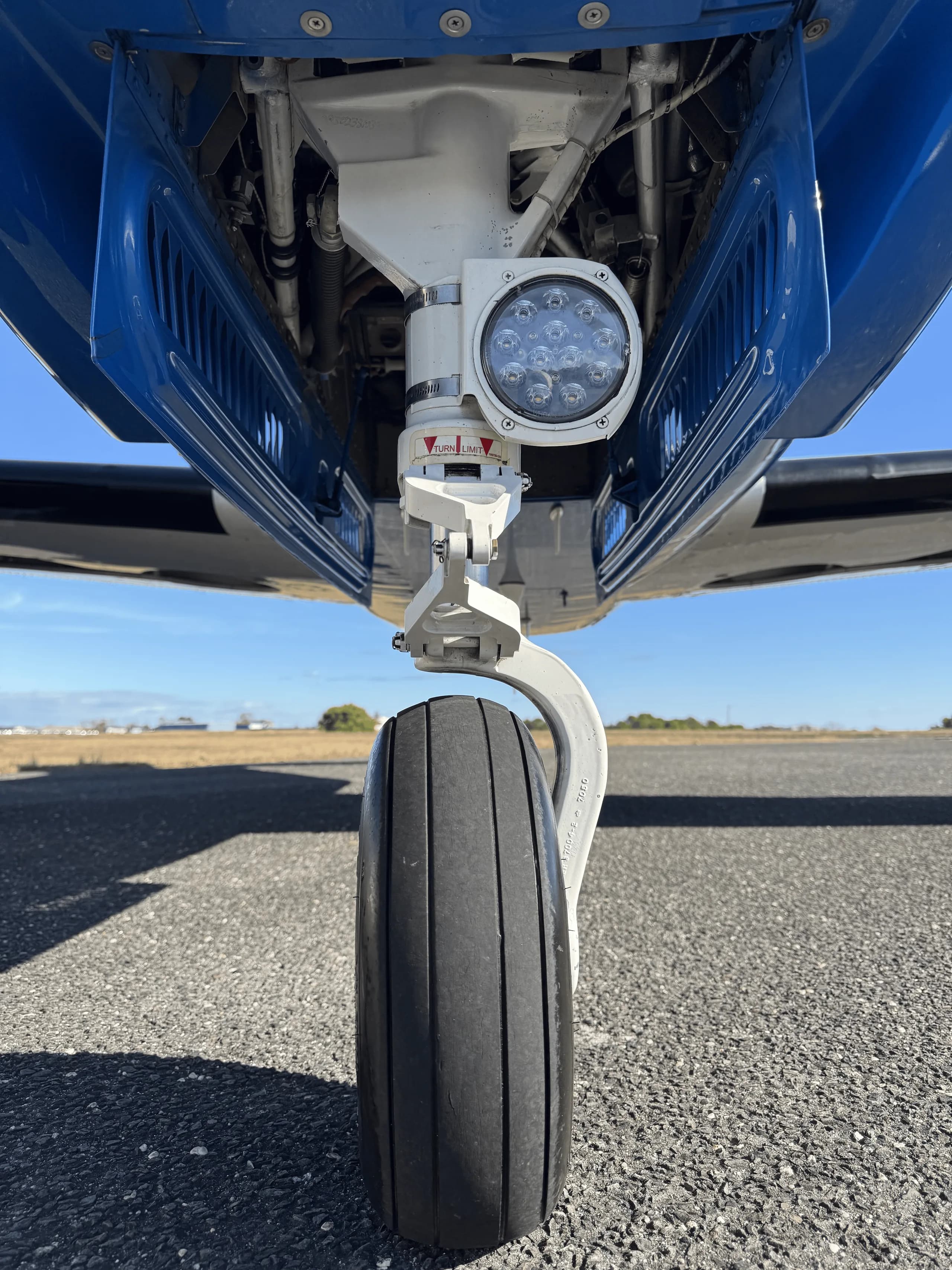 A close-up, low-angle view of the nose landing gear of a Piper M350 aircraft.