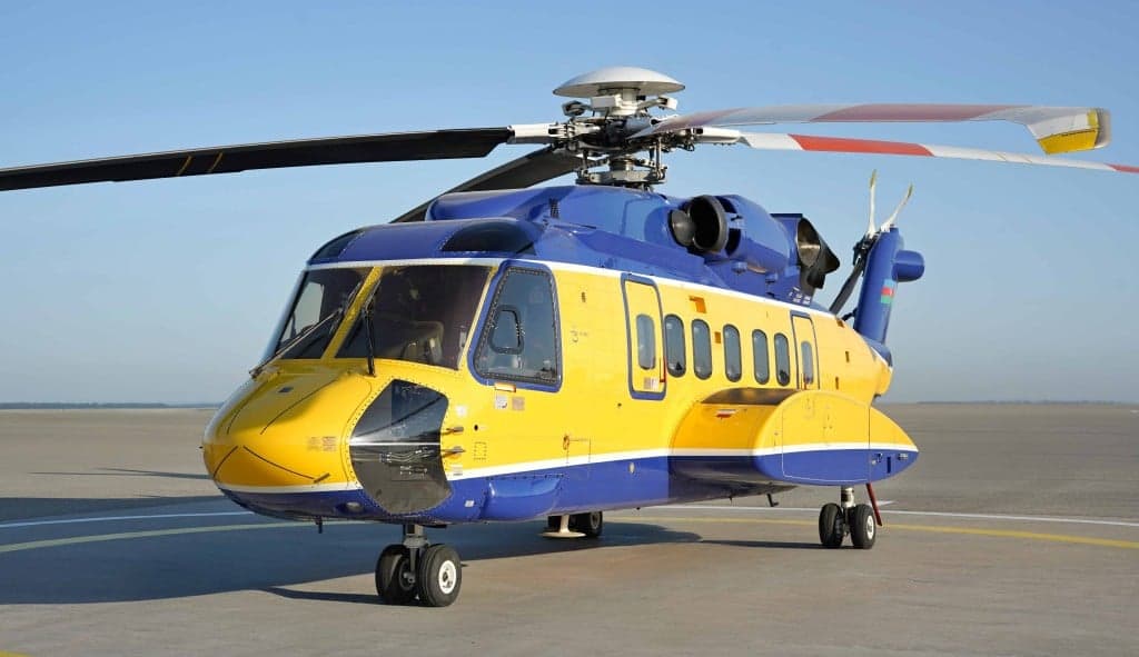 A blue and yellow helicopter with its door open on a helipad.