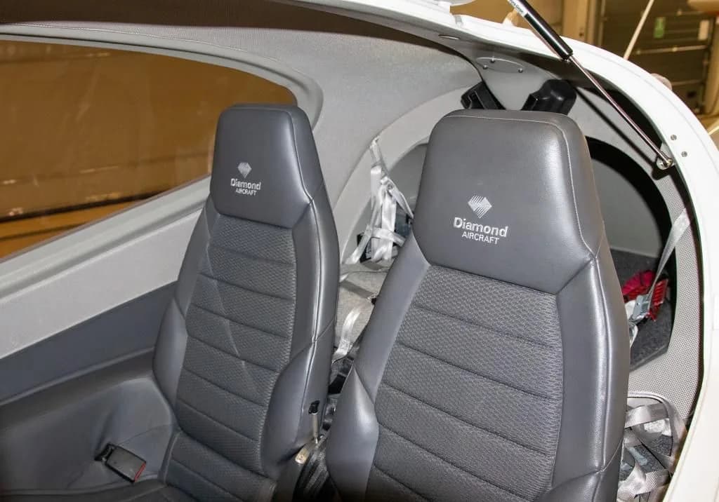 Two grey leather aircraft seats with "Diamond Aircraft" logo embroidered on the headrests.