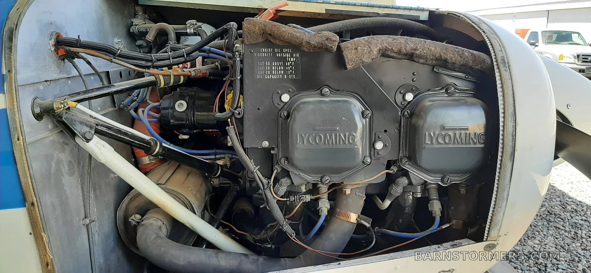 A close-up view of a Lycoming aircraft engine with its cowling open, showing various components and wiring.