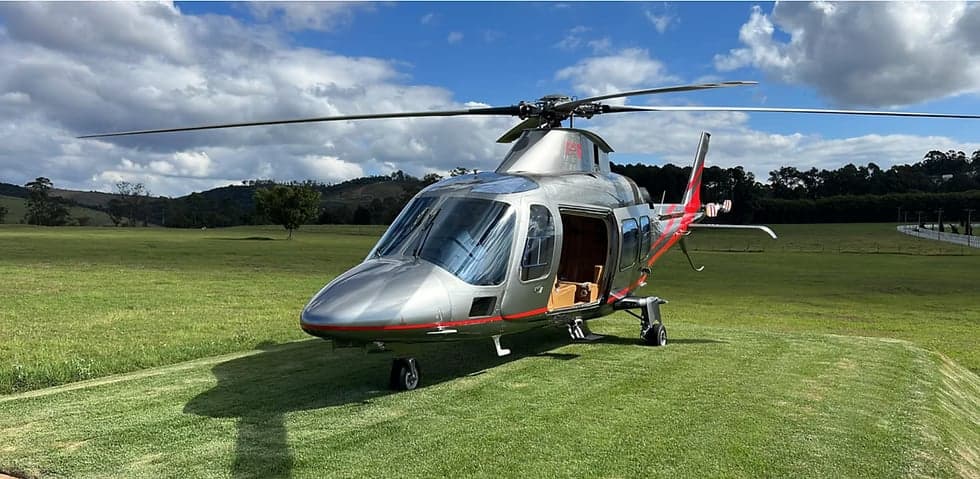AgustaWestland AW109SP helicopter parked on a grassy field.
