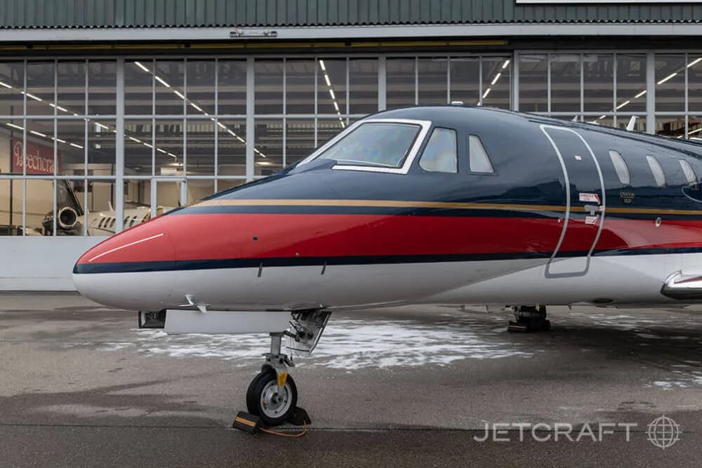 A close-up view of the nose and cockpit area of a dark blue, red, and white business jet.