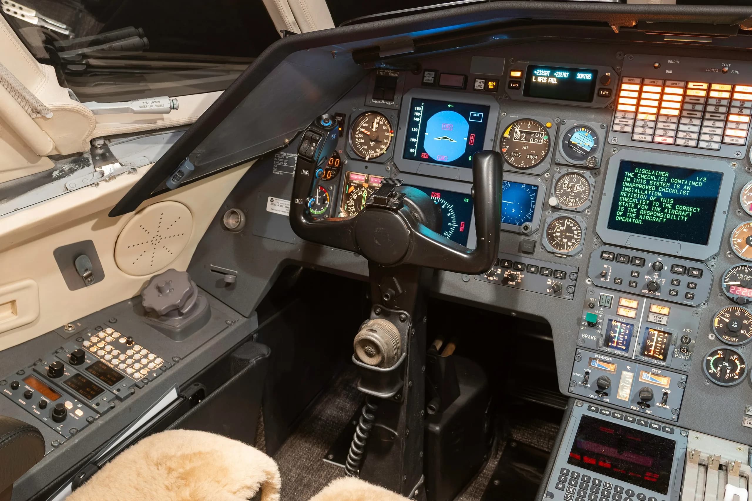 The cockpit of a business jet features a control yoke, multiple screens, and various instruments.