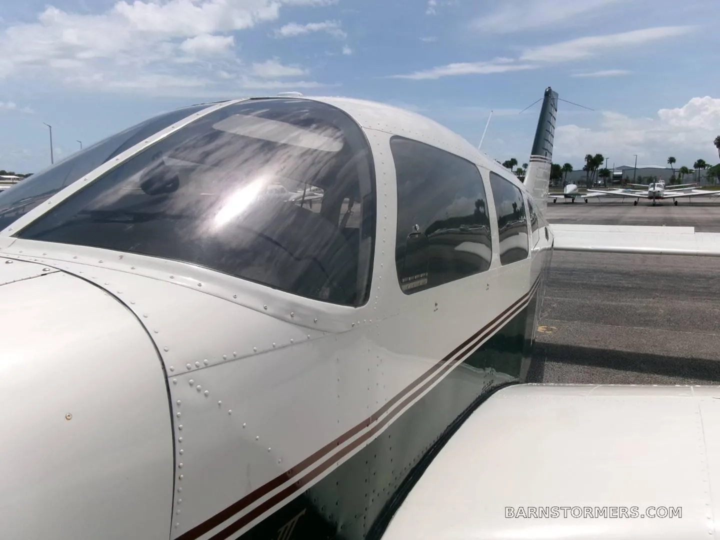 A close-up view of the cockpit and fuselage of a white and dark green Piper Archer II (N334AC) on an airfield.