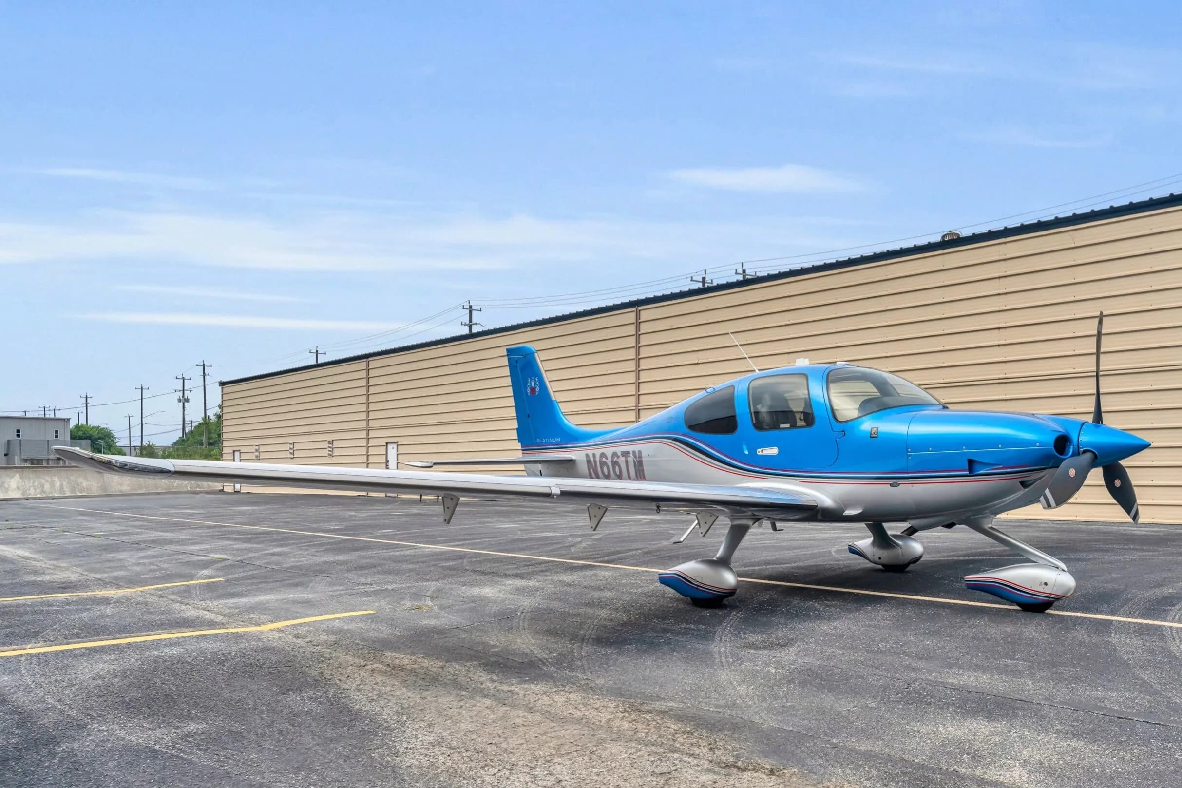 A three-quarter front view of the blue and silver Cirrus SR22T GTS aircraft N66TM, parked on an asphalt ramp.