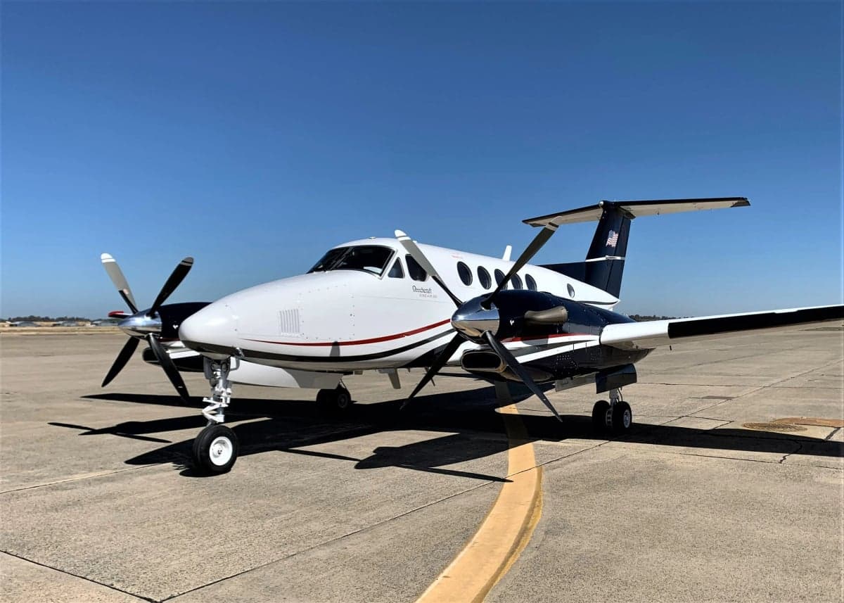 Beechcraft King Air on the tarmac with a white and black paint scheme.
