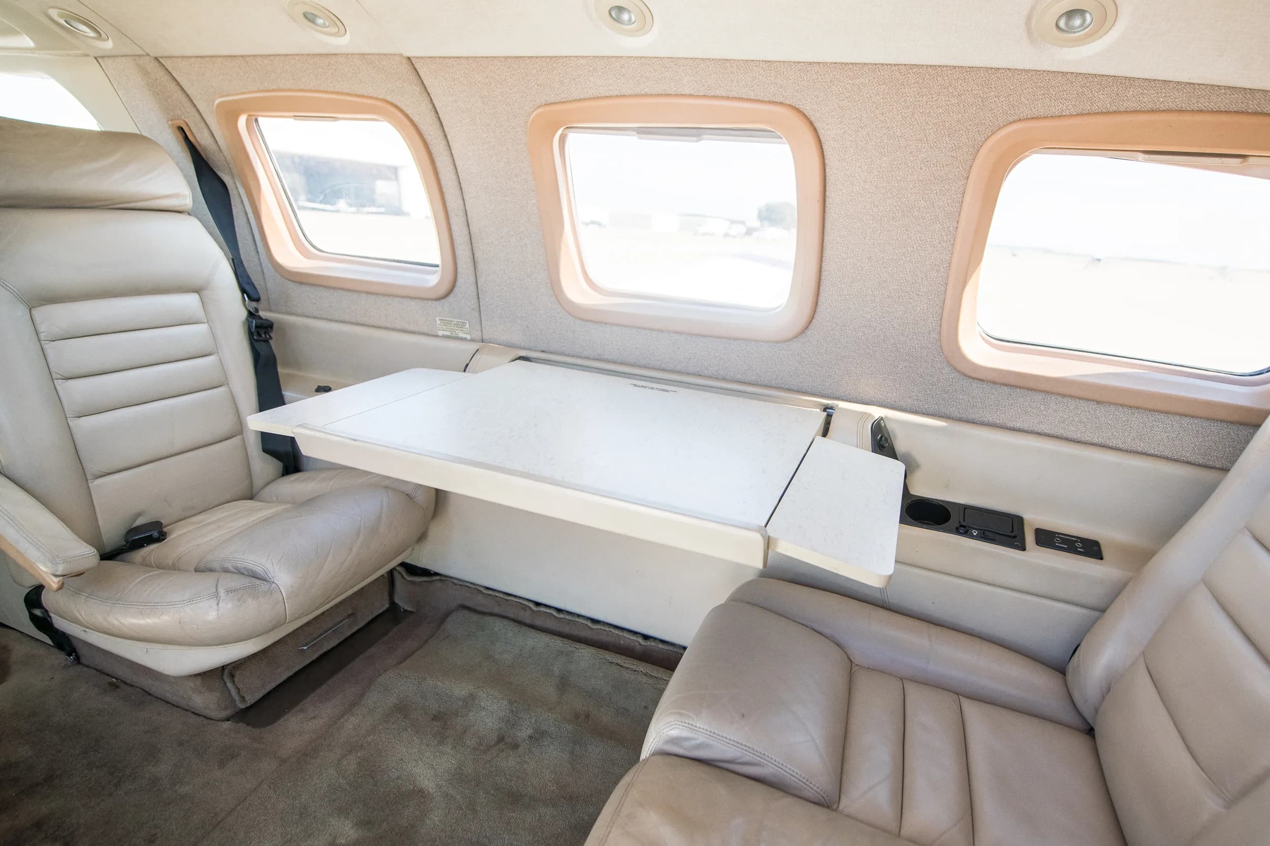 Another view of the N529WM aircraft's beige interior, showing two facing seats with a large fold-out table between them.