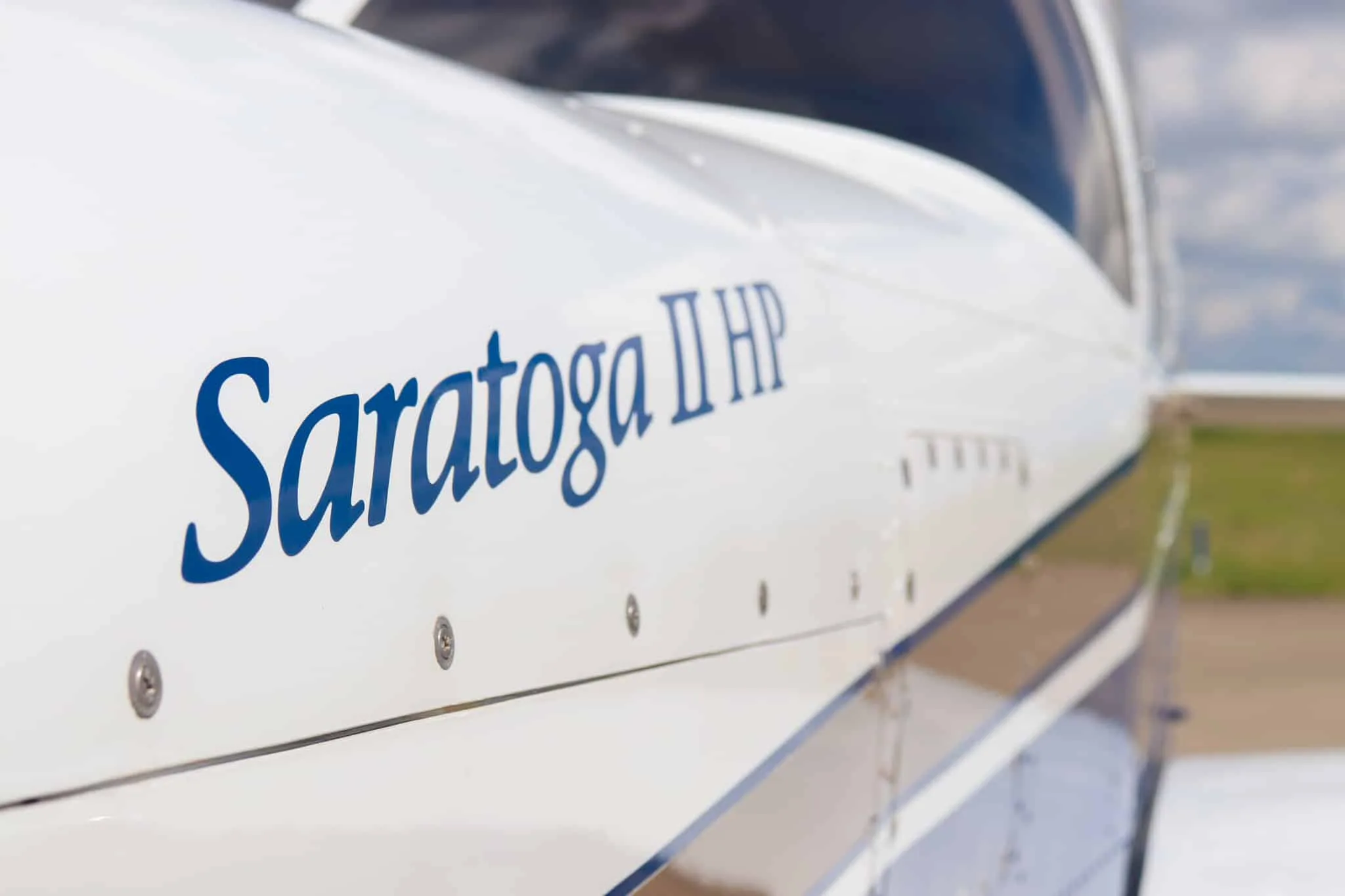 A close-up of the 'Saratoga II HP' text on the white fuselage of the aircraft.