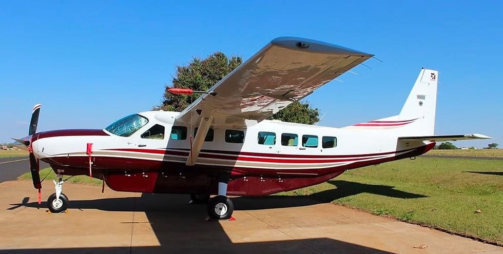 A maroon and white Cessna Caravan parked on the tarmac.