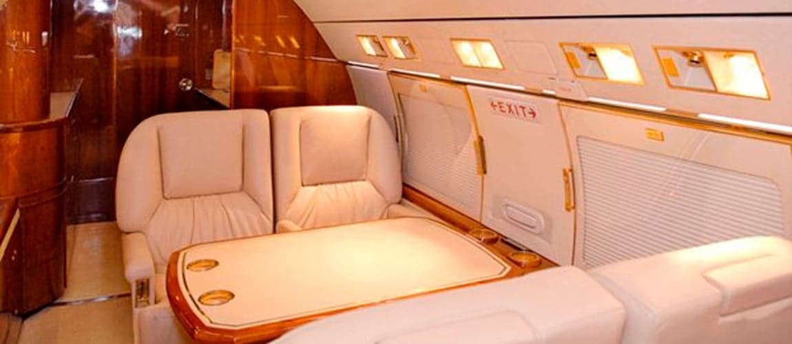 Interior of the aircraft with cream-colored seats and wood accents.