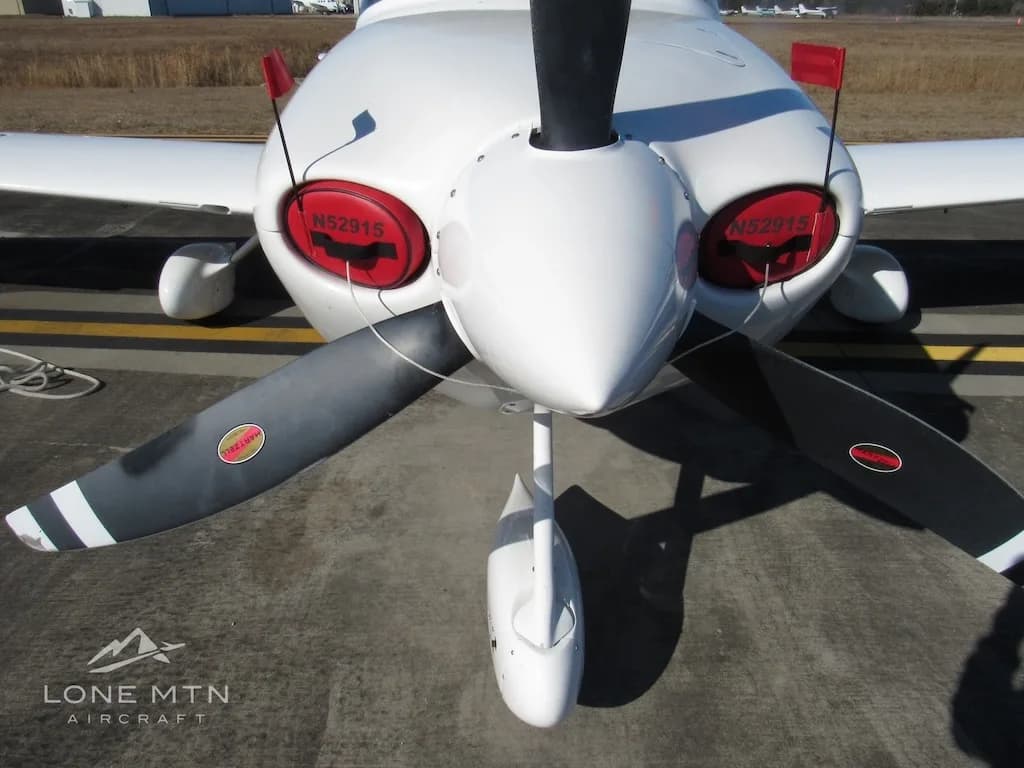 A close-up front view of the Cirrus SR20 propeller and nose, showing red engine inlet covers with "N52915".