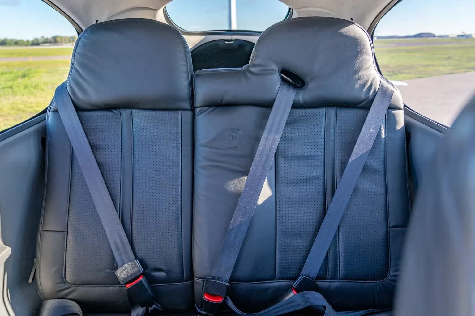 The black leather rear seats with seatbelts inside a small aircraft cabin.