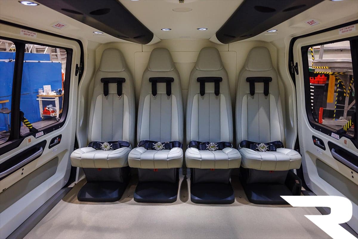 A view of four light grey passenger seats with dark seatbelts in the spacious cabin of an Airbus H160 helicopter.