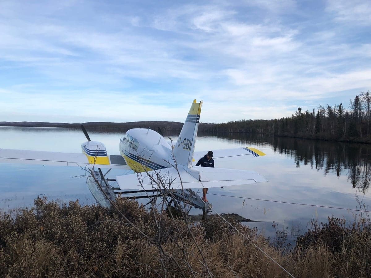 Yellow and white twin engine aircraft on floats, on a lake at dusk.