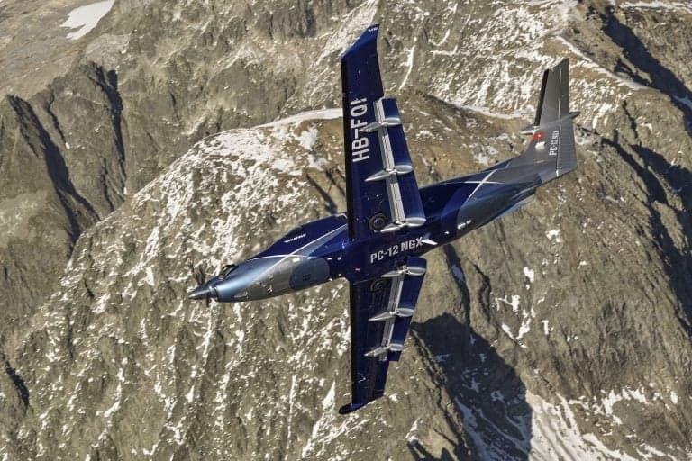 Pilatus PC-12 NGX in flight, top view, over mountains.