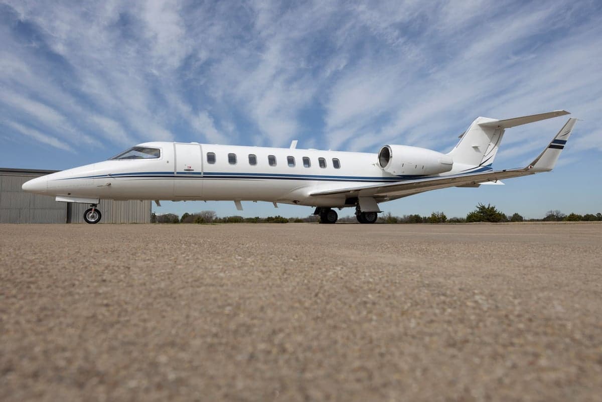 Side view of a white jet with blue accents parked on the tarmac.