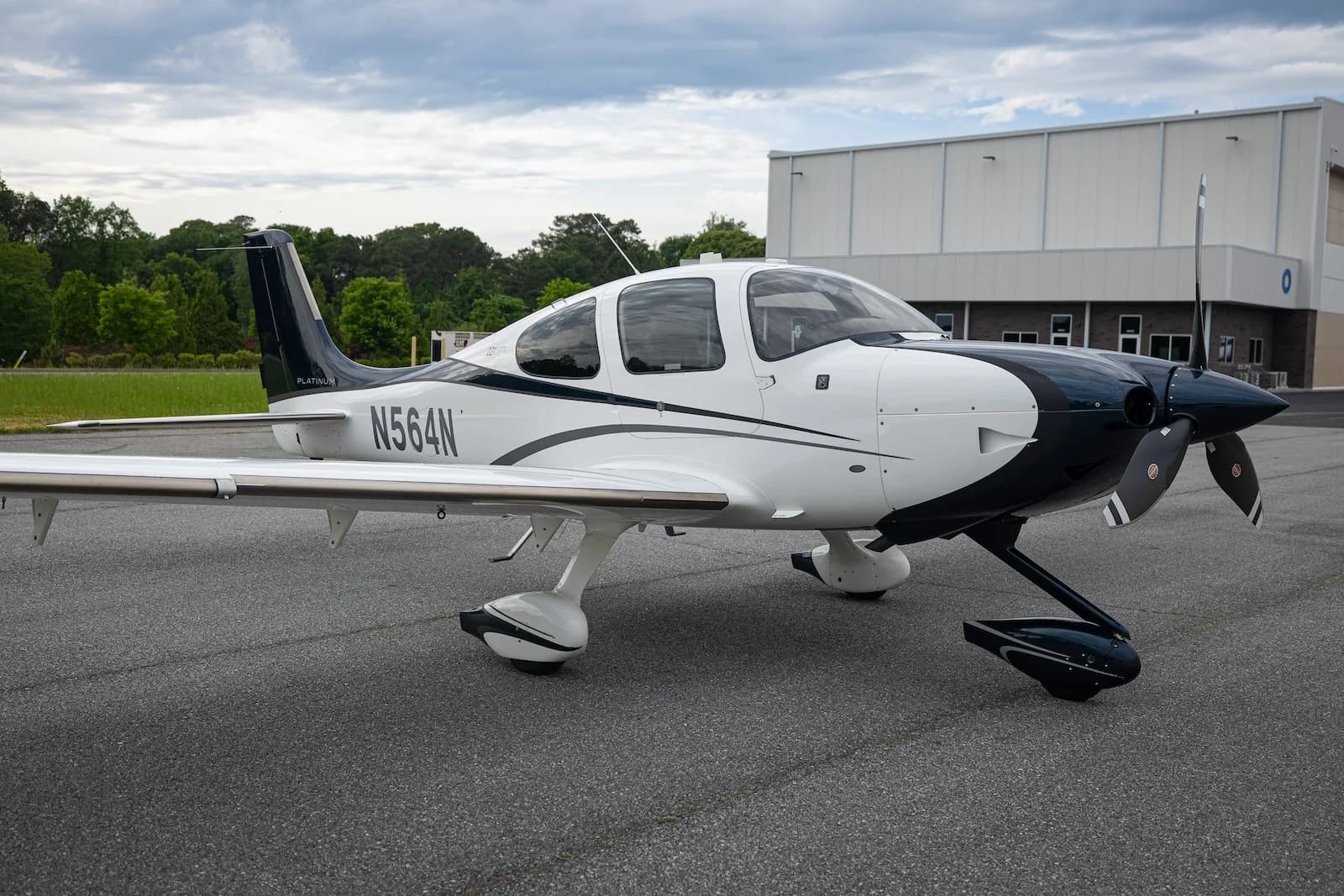 A white and dark blue Cirrus SR22T aircraft with registration N564N parked on an asphalt ramp, showing the nose and left side.
