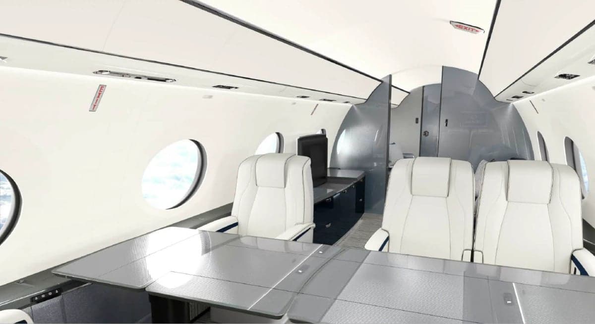 Interior view of the aircraft cabin with white leather seats and tables.