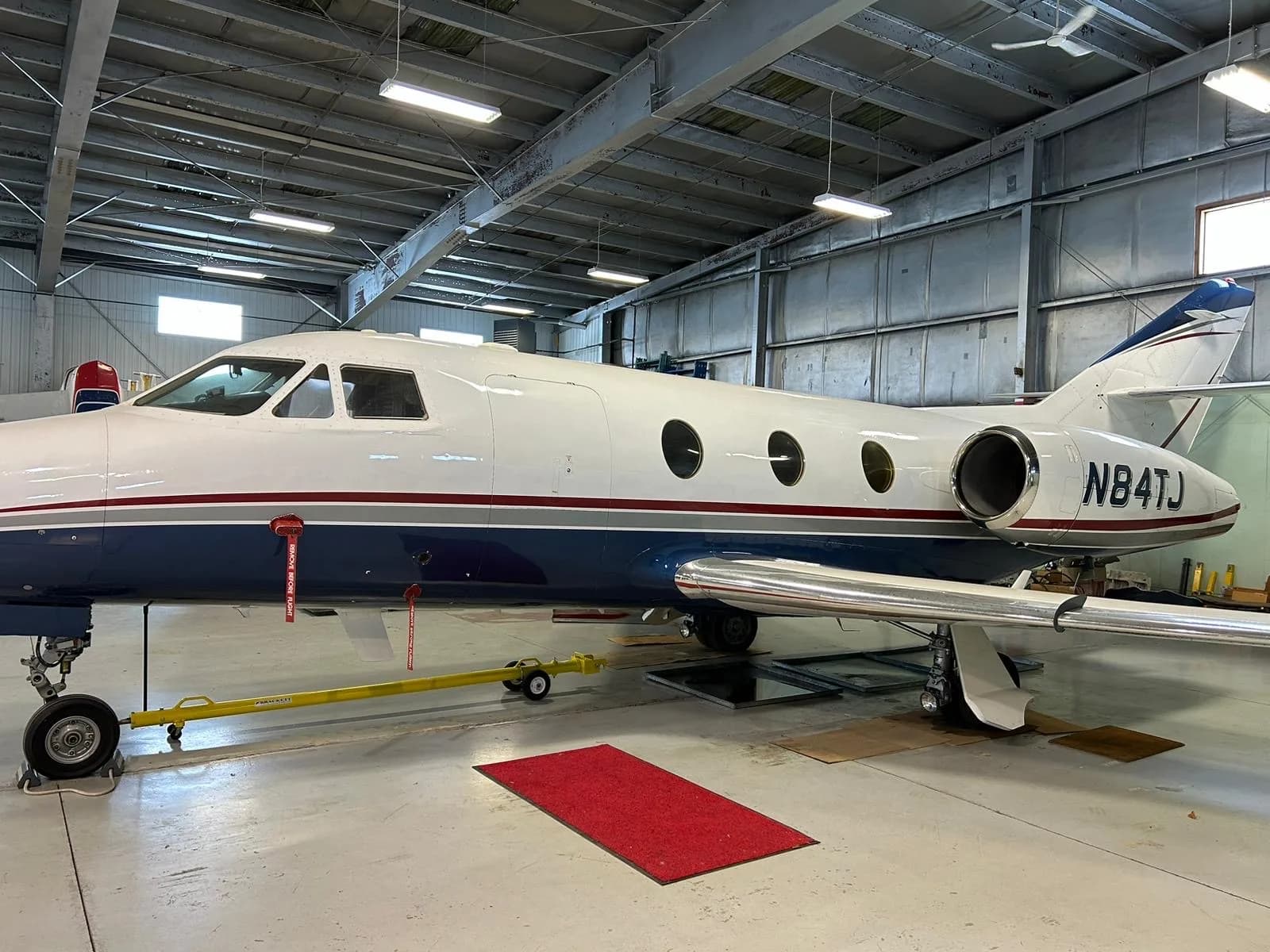 Side view of the aircraft N84TJ in a hangar.