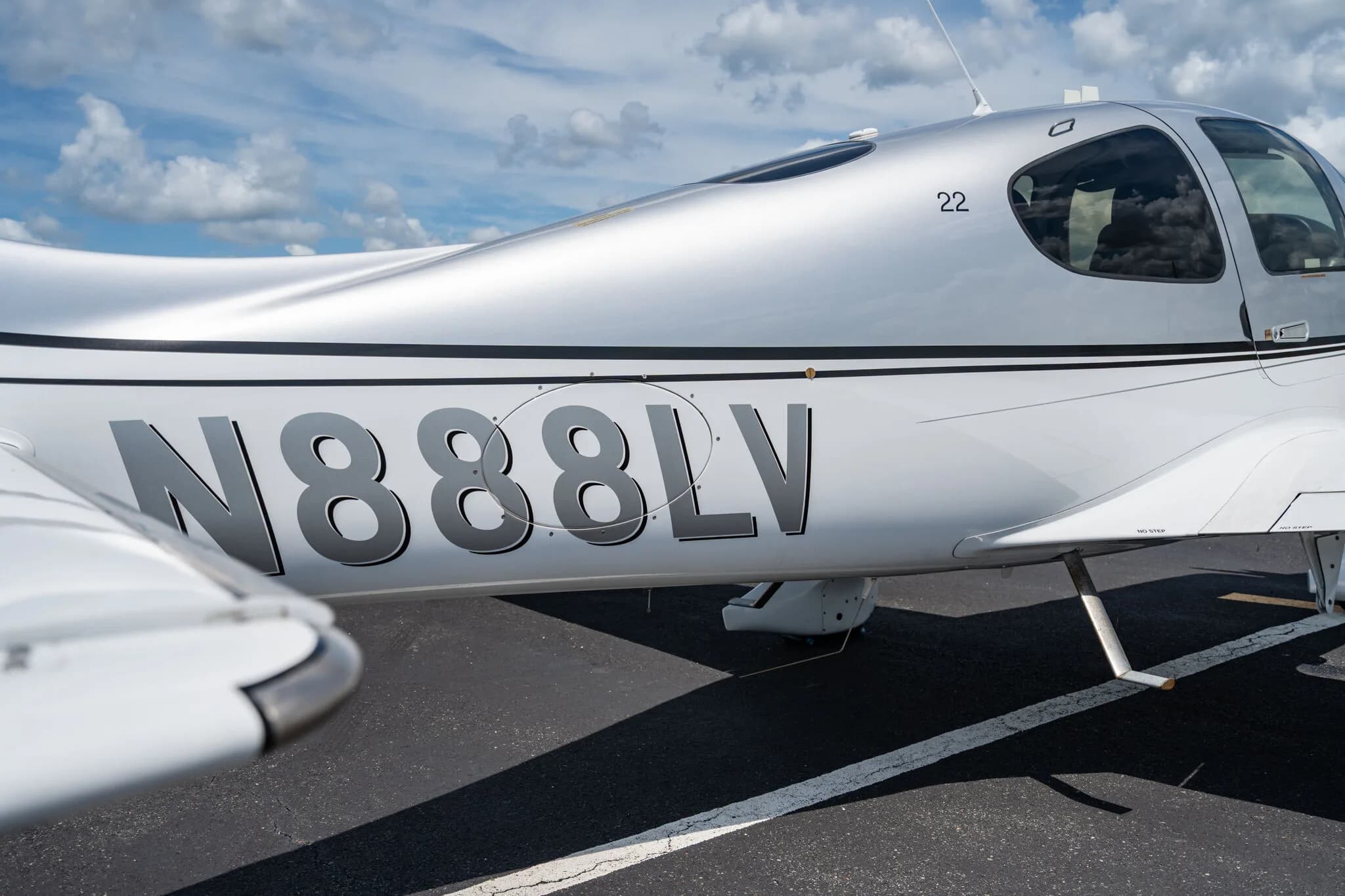 Close-up of the fuselage of a silver Cirrus SR22 aircraft showing the N-number N888LV.