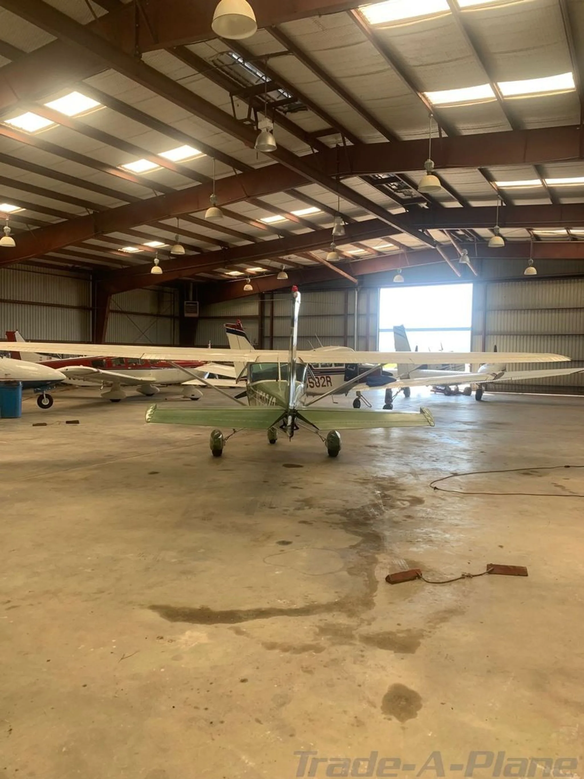 A rear view of the green and white Cessna aircraft N50846 parked in a hangar with other planes.