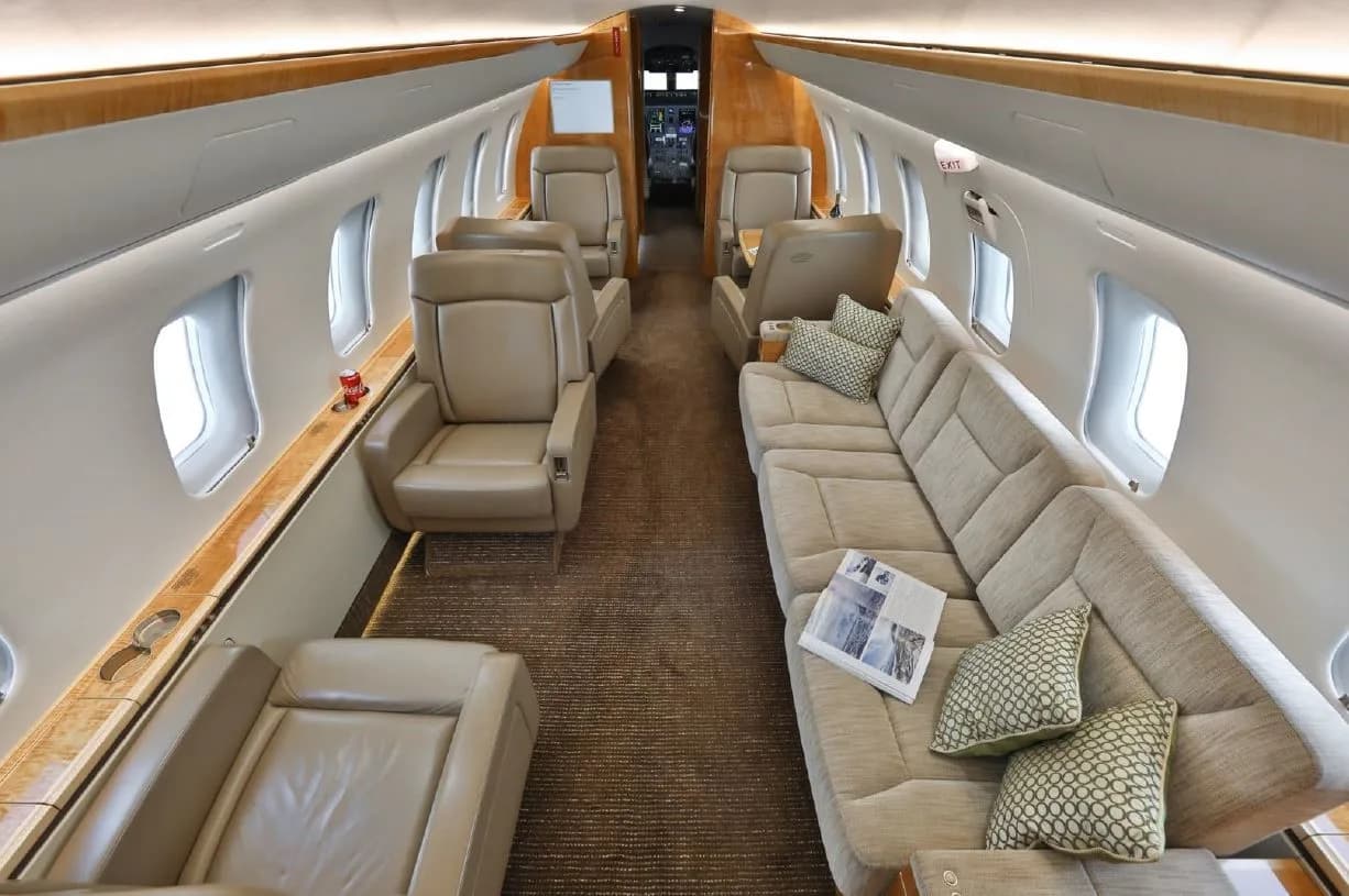 The luxurious interior cabin of a private jet features beige leather seats and a comfortable sofa.