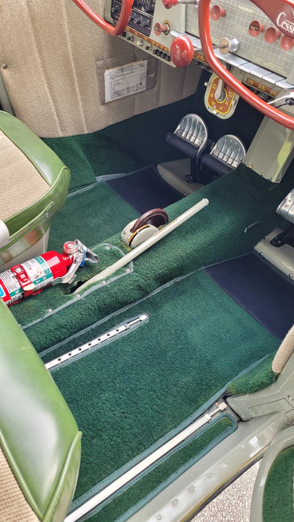 The interior of the Cessna 170 features green carpeting and beige seats.