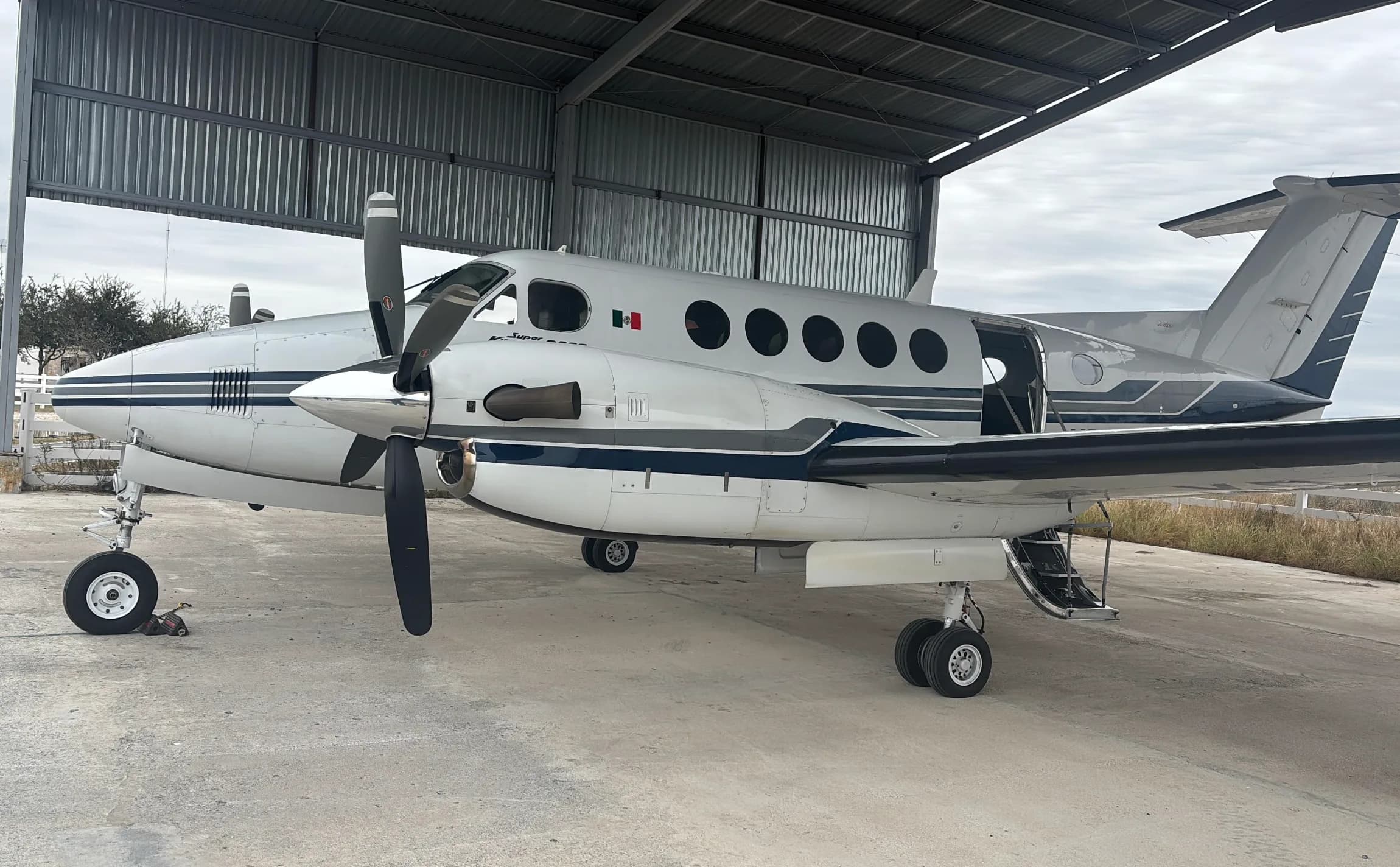 A Beechcraft King Air 350 is parked in a hangar with its door open.