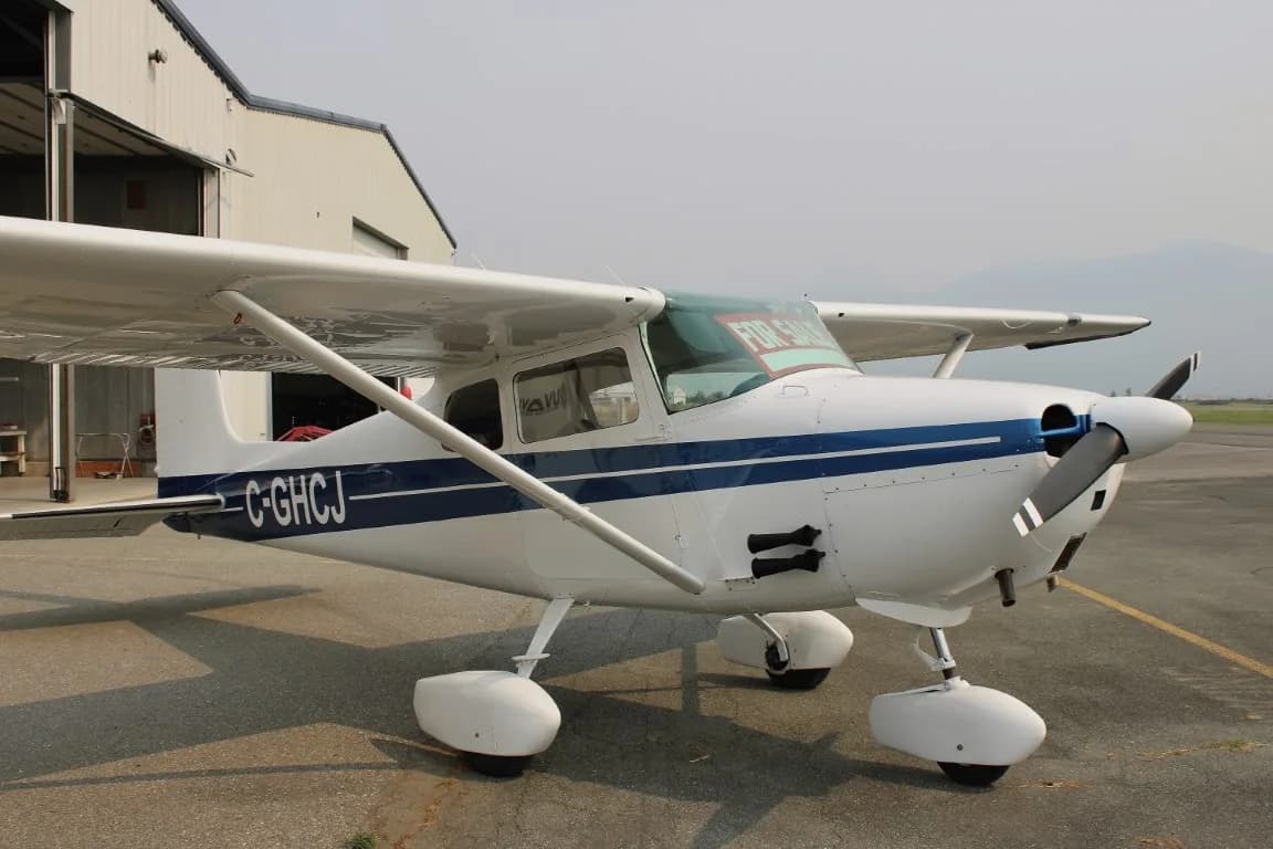 Cessna 172 with blue stripe parked on the tarmac.