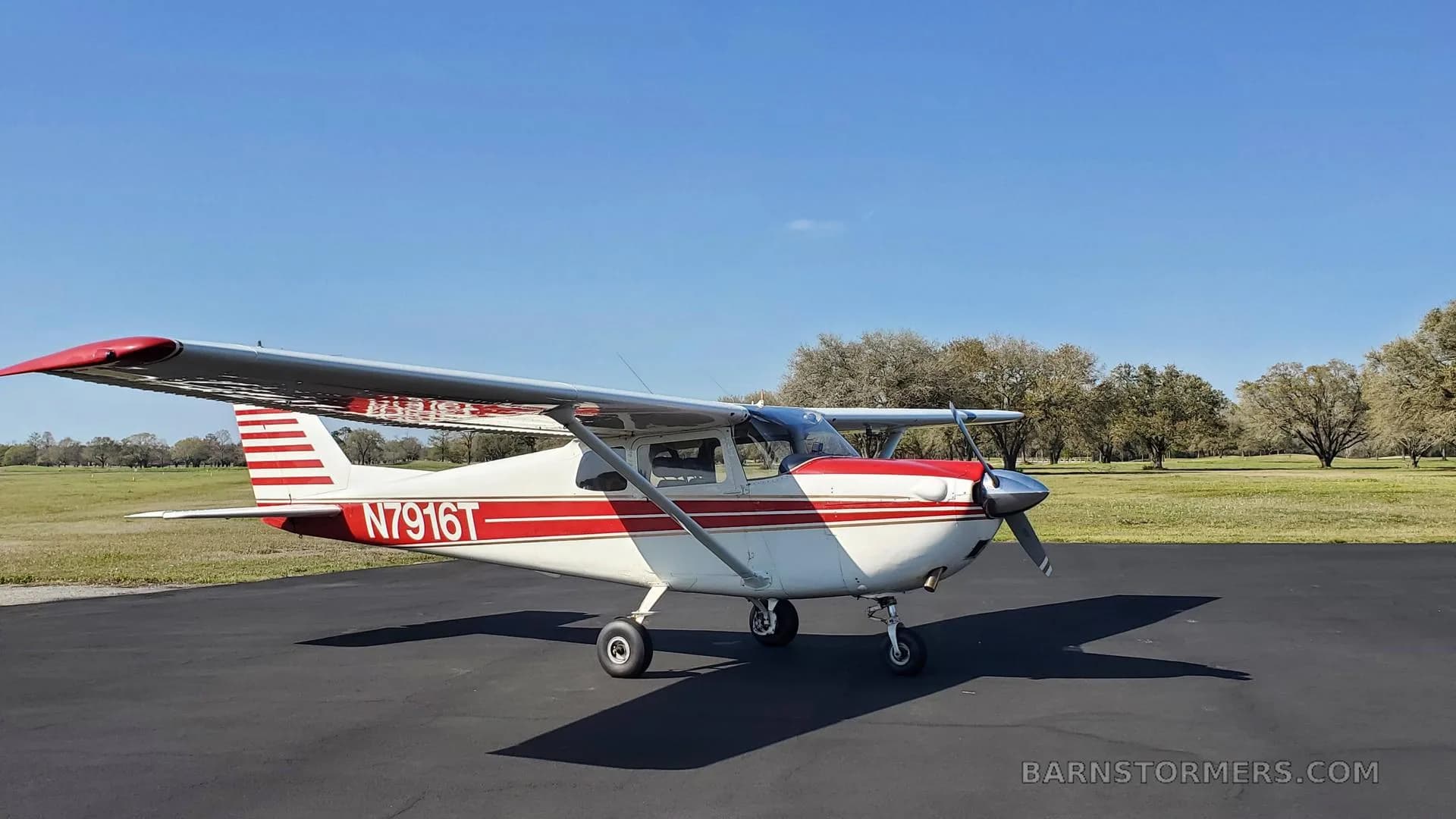 A white and red Cessna 172 with registration N7916T parked on an asphalt pad, viewed from the front.