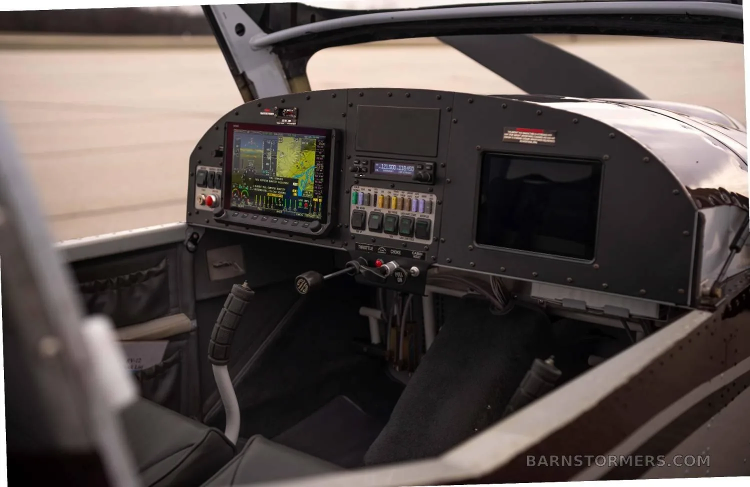 A detailed view of the aircraft's cockpit, showing the instrument panel with a large display and various controls from a slightly different angle.