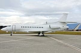 A white private jet parked on a runway.