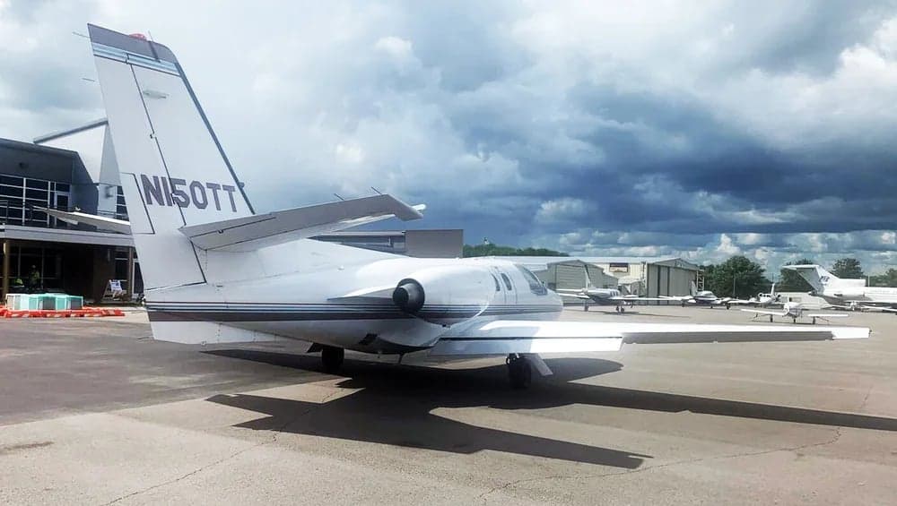 Rear quarter view of the white Cessna CitationJet N150TT on the tarmac.