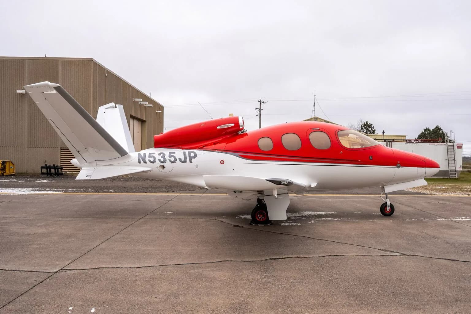 Right side profile of a red and white Cirrus Vision Jet (N535JP) on the tarmac.