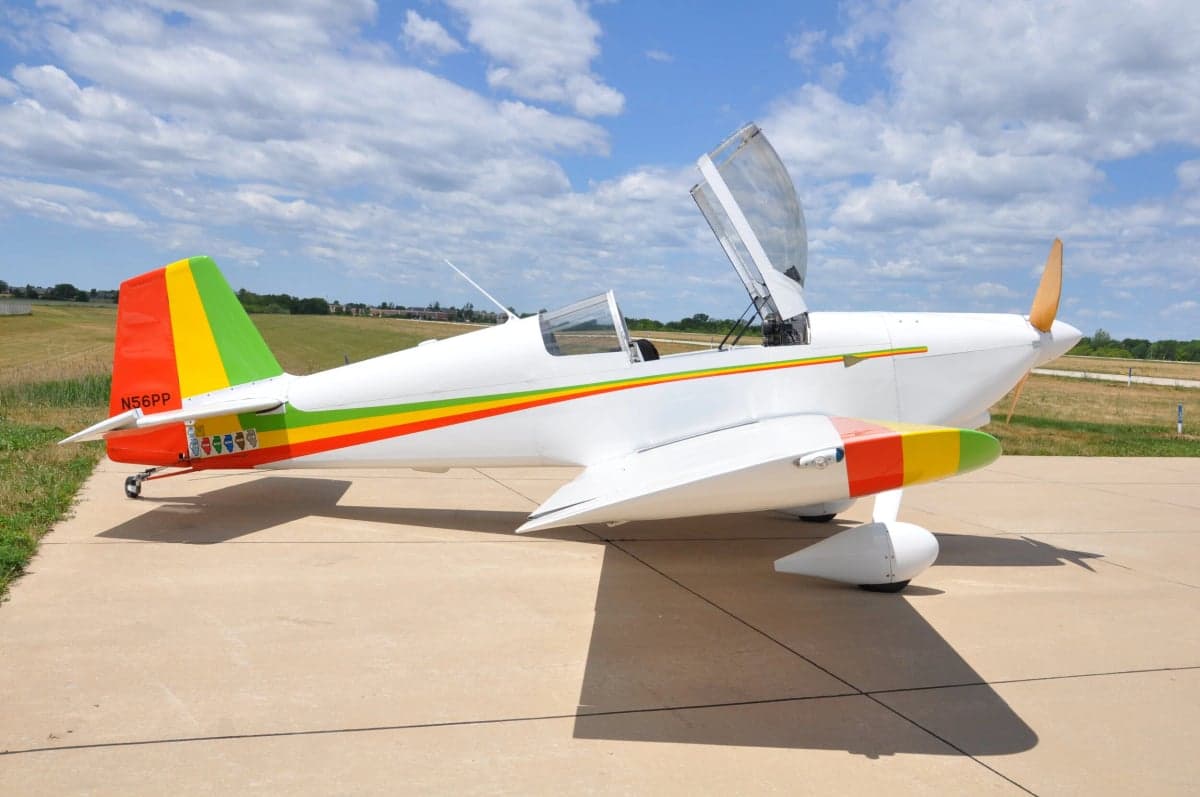 Side view of a white and colorful experimental aircraft with the canopy open.