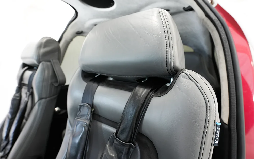 A close-up view of the gray leather headrest and seatbelt of an aircraft seat.