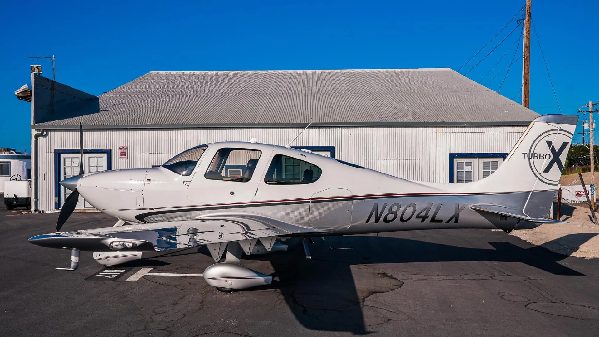 A side view of the white and silver Cirrus SR22T aircraft N804LX with its wings reflecting the sunlight.