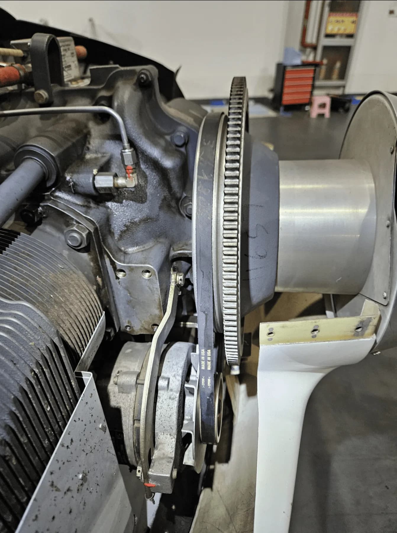 A close-up view of an aircraft engine with exposed components and a drive belt.