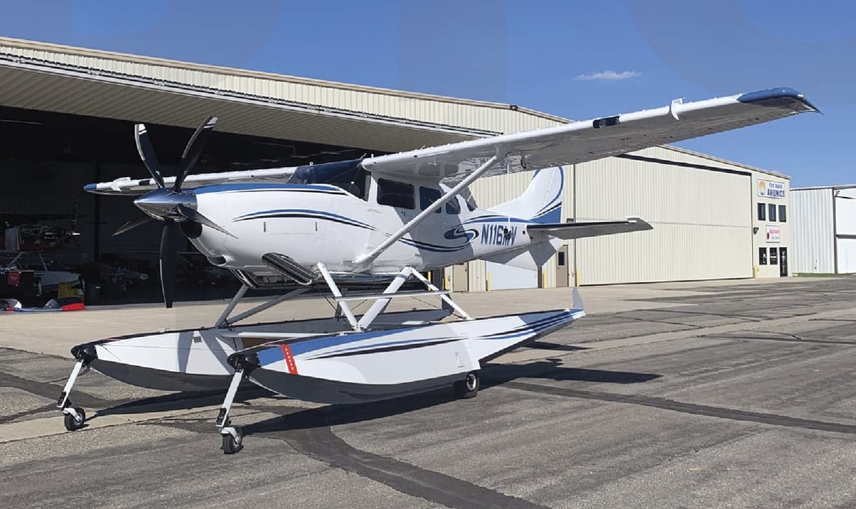A Quest Kodiak aircraft on floats is parked outside a hangar.