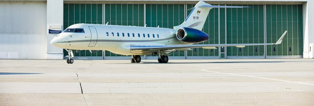 A white Bombardier Challenger aircraft parked in front of a hangar.