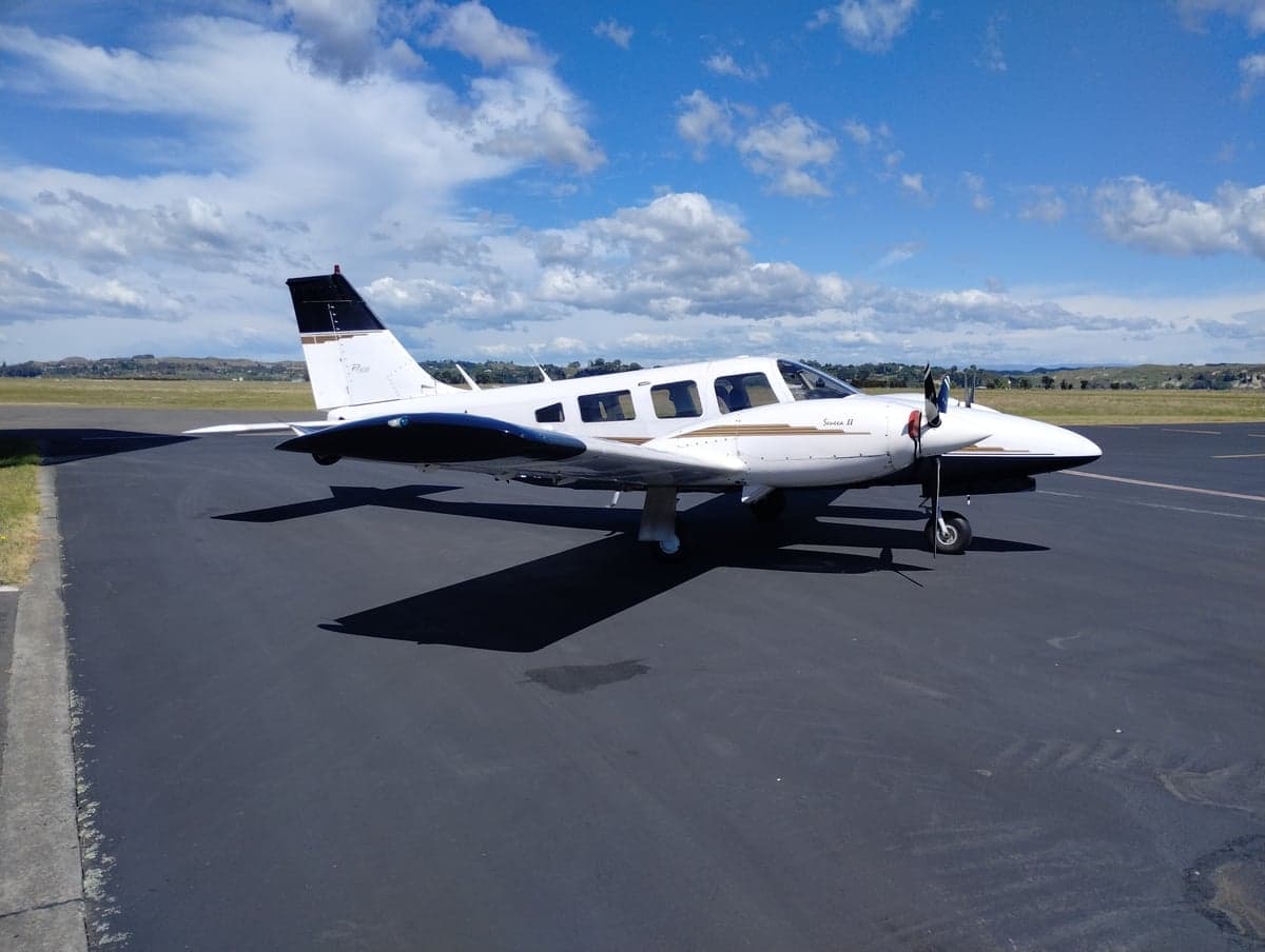 A white and black Piper Seneca II aircraft parked on the tarmac.