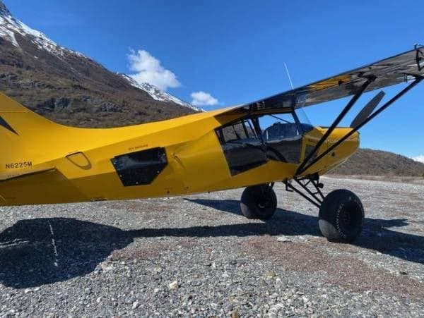 A yellow Maule aircraft with registration N6225M is parked on a gravel field.