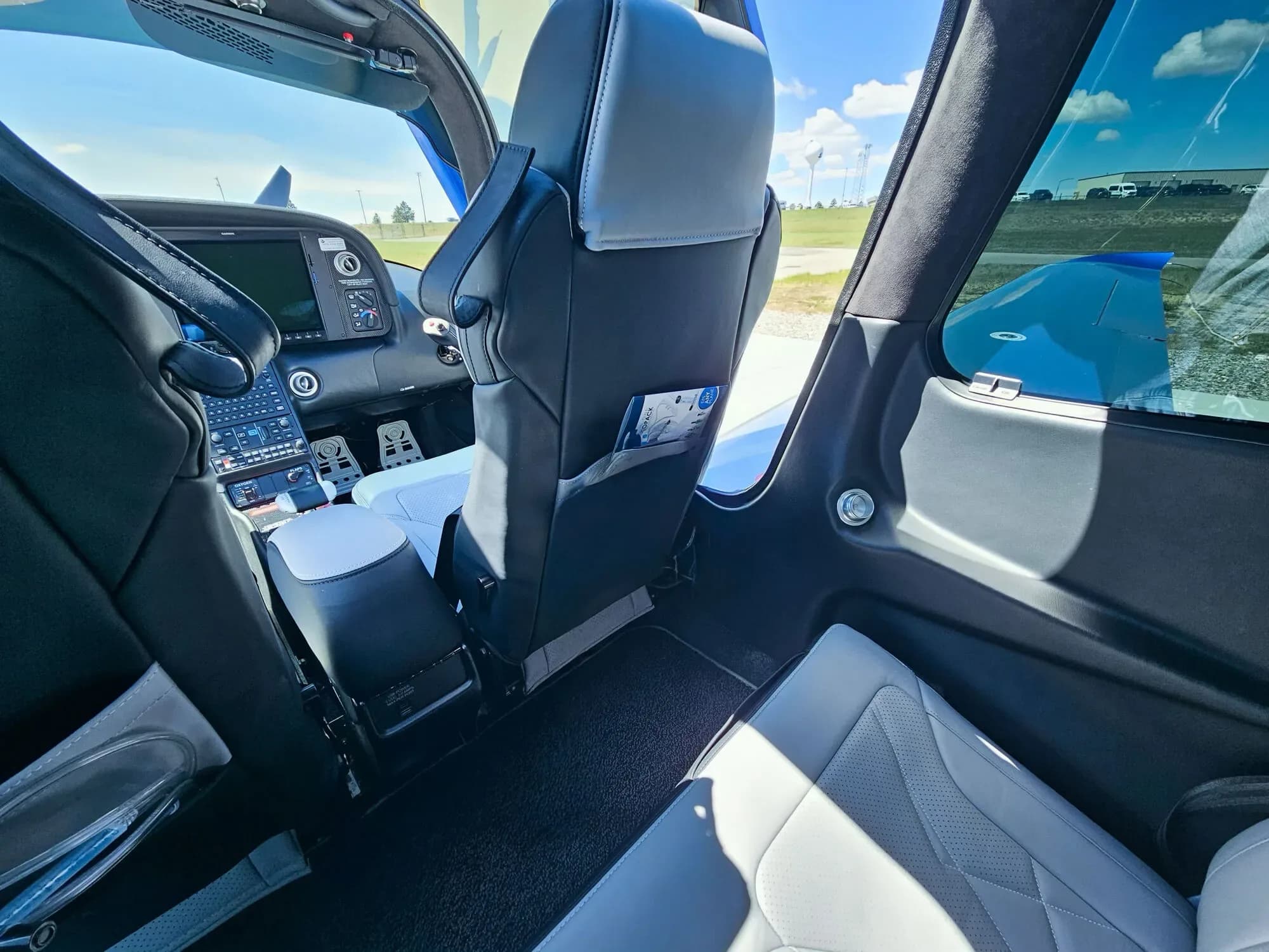 The light gray and black leather interior of the Cirrus SR22T cabin, showing the rear seats and a glimpse of the cockpit.