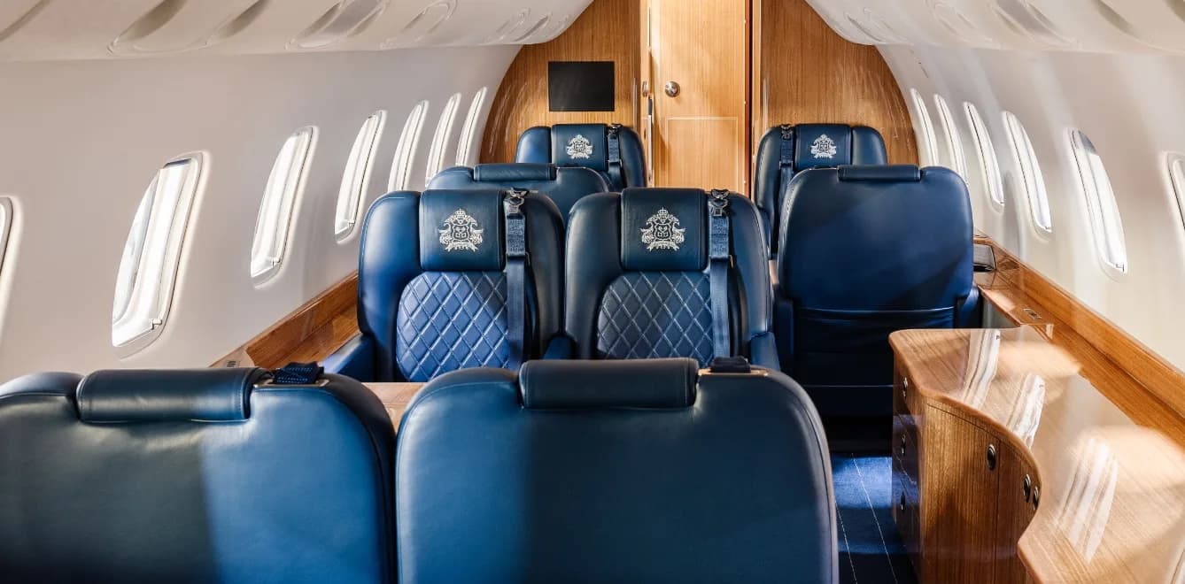 View of the aircraft cabin with blue leather seats and wood paneling.