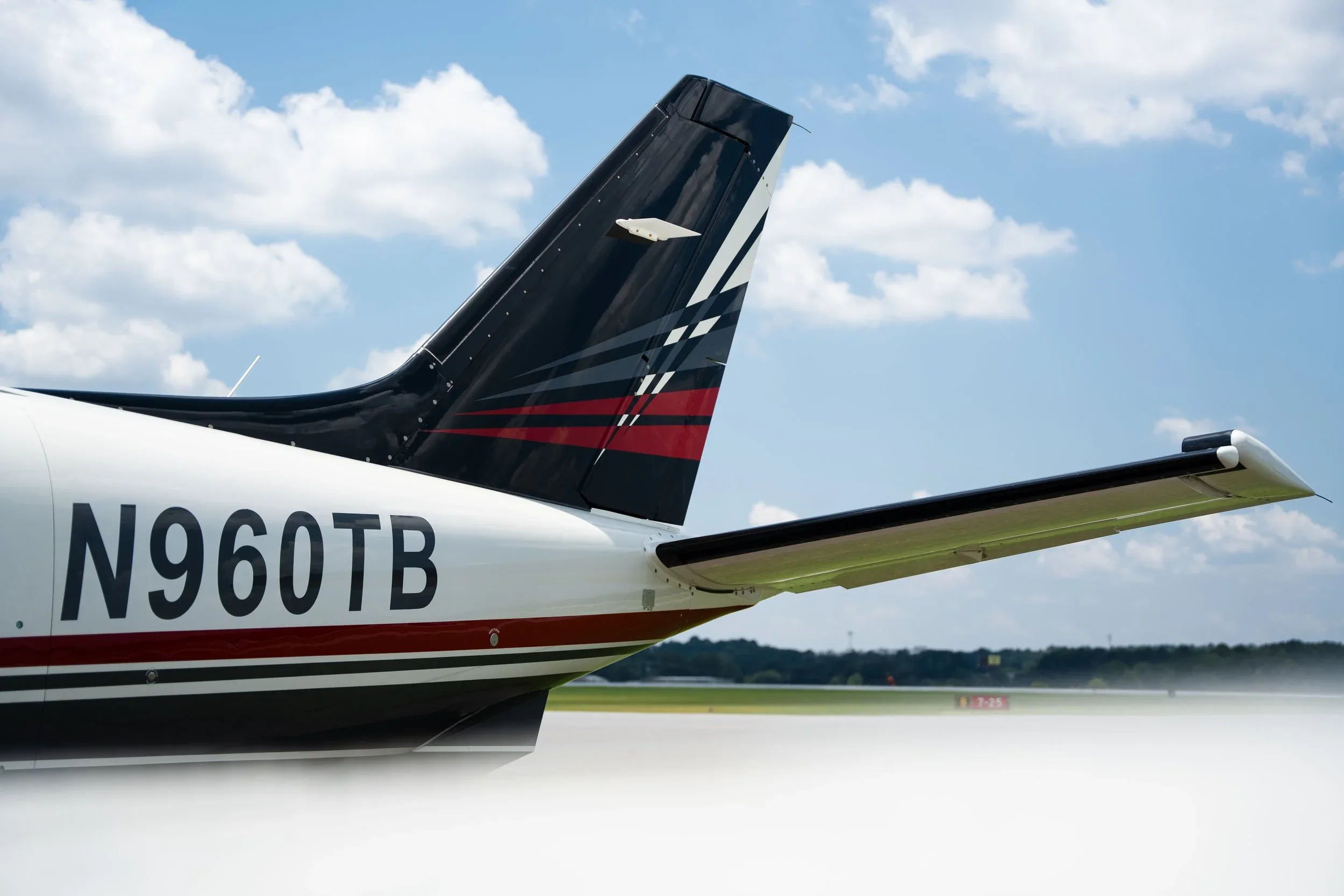 A close-up of the tail section of a white and black TBM 960 aircraft, showing the registration N960TB and tail paint scheme.