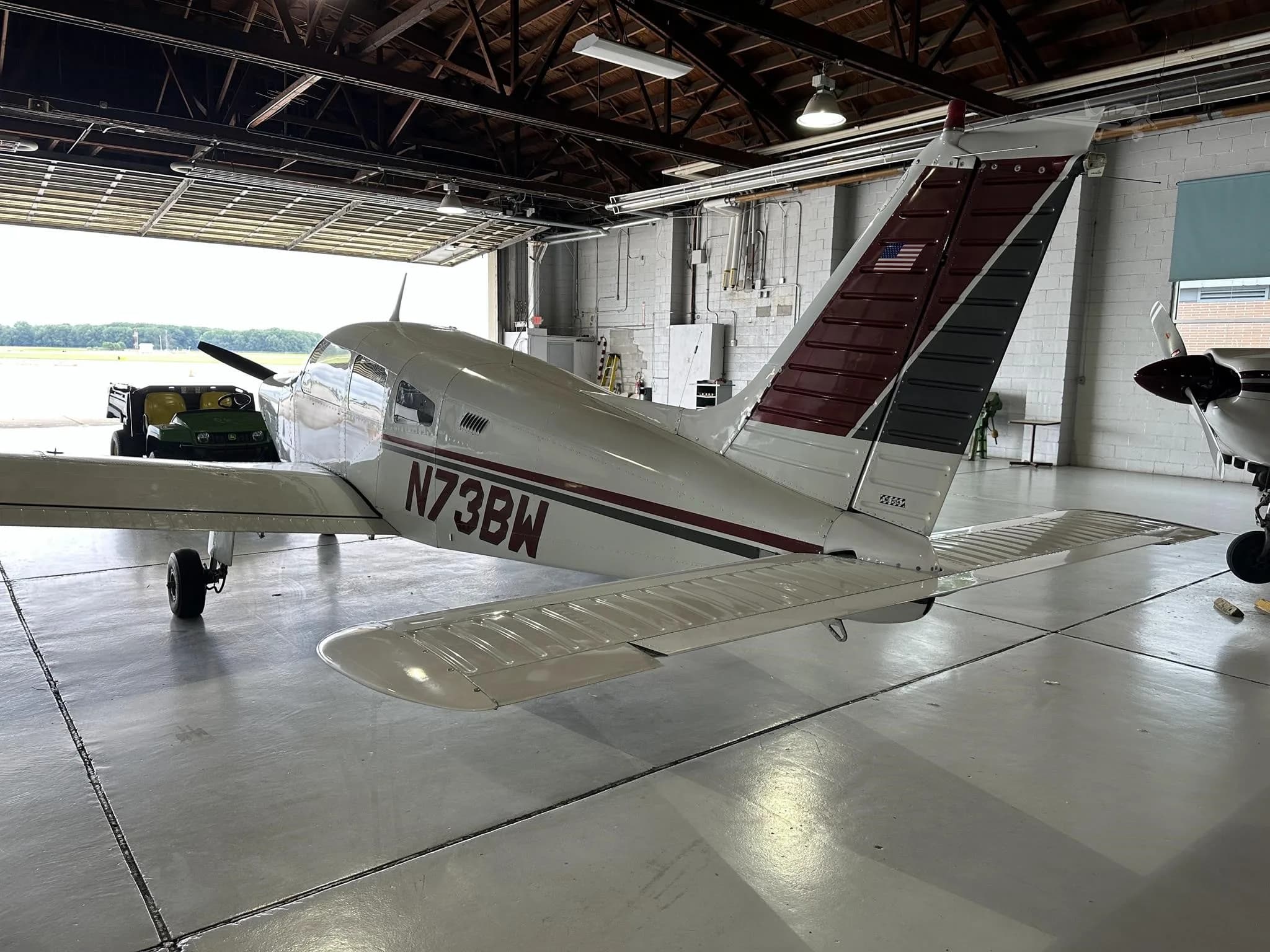 A rear-left view of the N73BW aircraft, showing its tail and part of the hangar entrance.