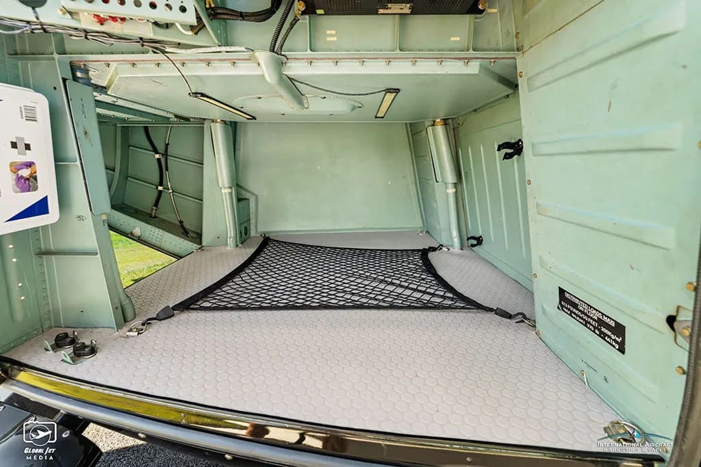 Interior view of an empty helicopter cargo compartment with a grey textured floor and a black net.